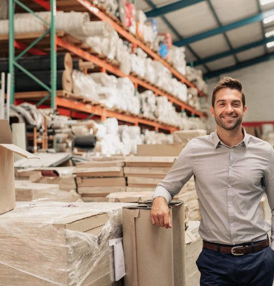 Portrait,Of,A,Smiling,Warehouse,Manager,Leaning,Against,Some,Stock